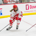 Wisconsin Sophomore Kirsten Simms, in her white and red Wisconsin jersey, skates around the ice with the puck.