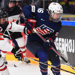 Hayley Scamurra, in the USA Hockey navy jersey, moves the puck along the boards with a Canada opponent right at her back
