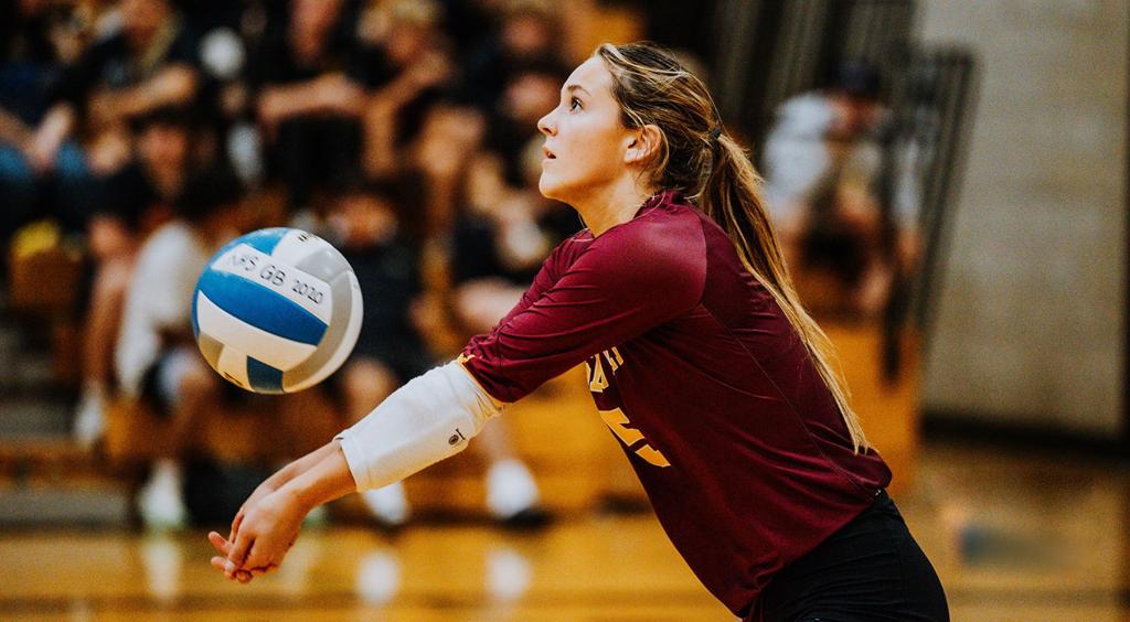 Image of Minneapolis Roosevelt High School Teddy varsity volleyball player setting the ball for her teammate during a match at Roosevelt’s Jack Wells Gymnasium